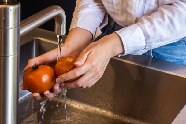 Πρόσωπο που πλένει ντομάτες με νερό στο νεροχύτη - Φωτογραφία, εικόνα