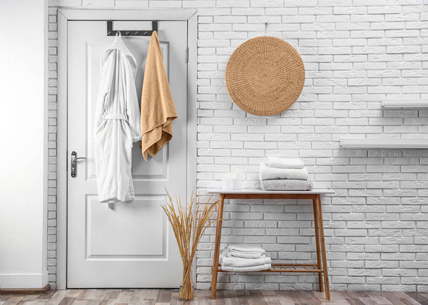Soft comfortable bathrobe and towel hanging on door in stylish room interior - Fotó, kép