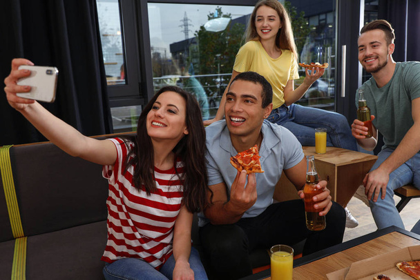 Happy young people with delicious pizza taking selfie in cafe - Fotoğraf, Görsel
