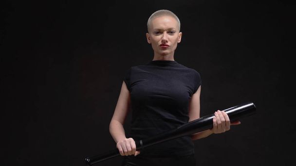 beautiful short haired blond woman  with a baseball bat on black background - Fotó, kép