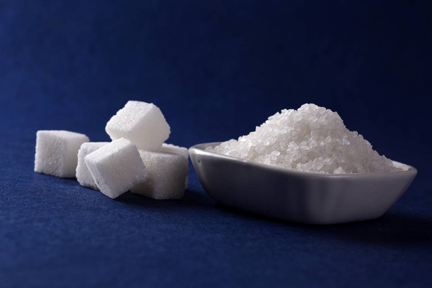 Cubos de açúcar com açúcar na placa branca no fundo azul
 - Foto, Imagem
