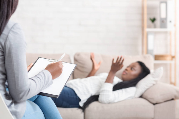 Молодая черная женщина лежит на диване в офисе психотерапевта
 - Фото, изображение