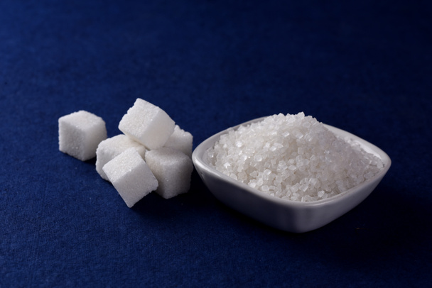 Cubos de Azúcar con Azúcar en plato blanco sobre fondo azul
 - Foto, imagen