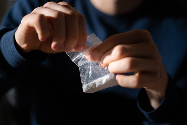 drugsverslaafde handen met een kleine verpakking met wit poeder - Foto, afbeelding