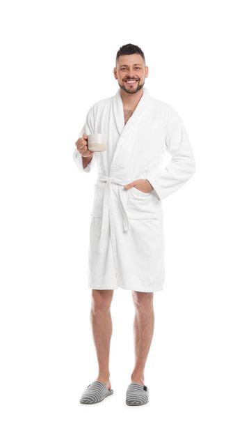 Handsome man with cup of coffee wearing bathrobe on white backgr - Foto, Imagem