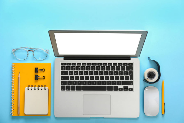 Laptop and office stationery on light blue background, flat lay - Fotó, kép