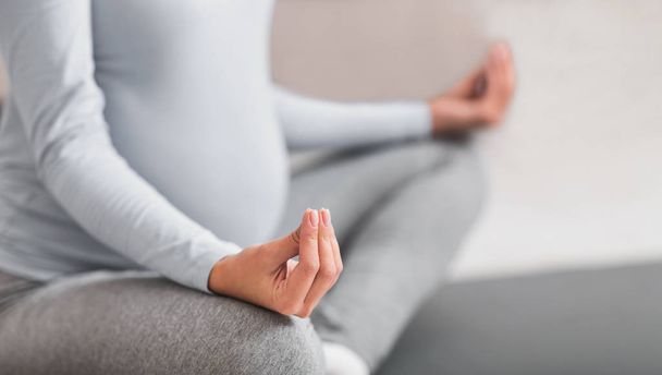 Vágott kép fiatal várandós meditáló otthon - Fotó, kép