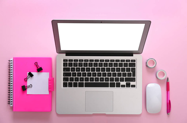 Modern laptop and office stationery on pink background, flat lay - Fotó, kép
