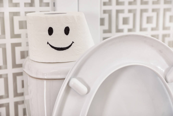 Roll of paper with funny face on toilet tank in bathroom, closeup - Photo, Image