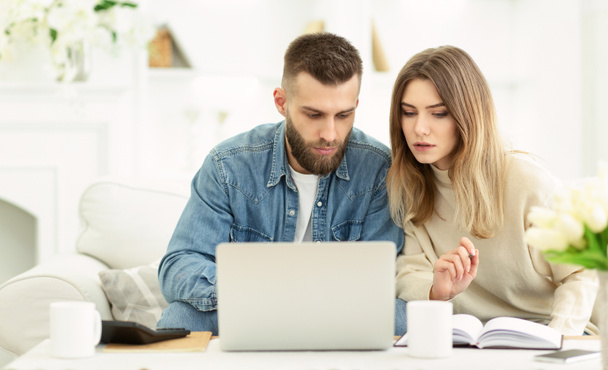 Millennial couple managing expenses with laptop and making notes - Foto, Imagem