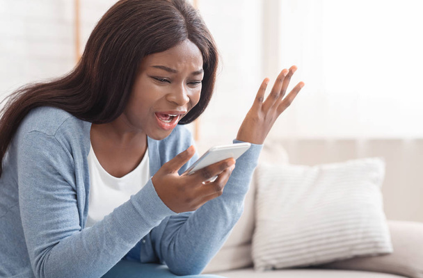 Portrait of young black woman shouting at mobile phone at home - Foto, Imagem