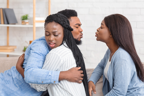 infiel afro hombre besos otra mujer mientras abrazando con su esposa
 - Foto, Imagen