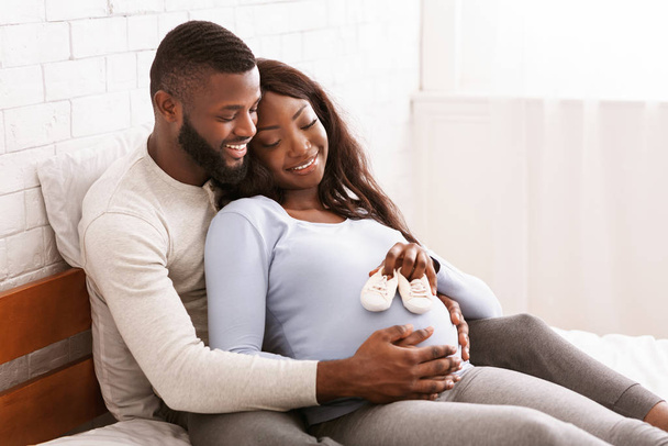 Terhes pár, akik jövő baba kis csizmát tesznek a hasukra. - Fotó, kép