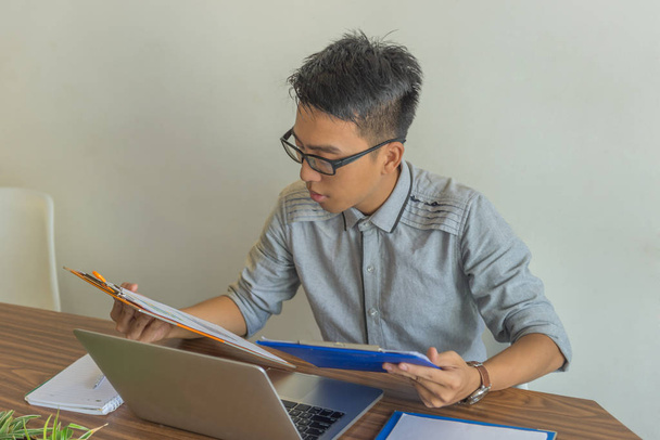 Gerente asiático leyendo informes en la oficina
 - Foto, imagen