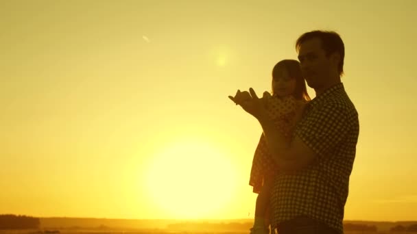 Ο μπαμπάς χορεύει με ένα παιδί στην αγκαλιά της στον ήλιο. έννοια της ευτυχισμένης παιδικής ηλικίας. Πατέρας και μικρή κόρη στροβιλίζονται στο χορό το ηλιοβασίλεμα. Ευτυχισμένο παιδί παίζει με τον πατέρα του. έννοια της ευτυχισμένης οικογένειας - Πλάνα, βίντεο