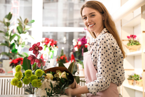 Professional florist with bouquet of fresh flowers in shop - Fotó, kép