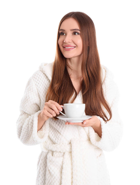 Young woman in bathrobe with cup of drink on white background - Φωτογραφία, εικόνα