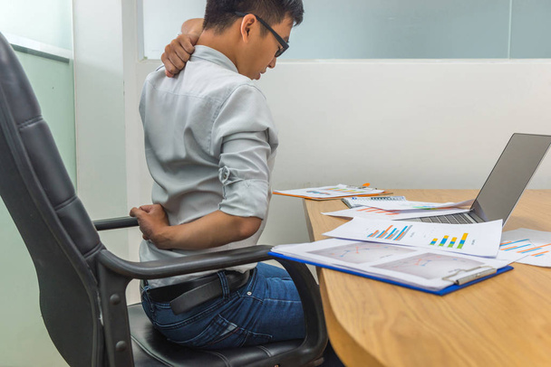 Tired businessman sitting at workplace having neck pain and headache - 写真・画像
