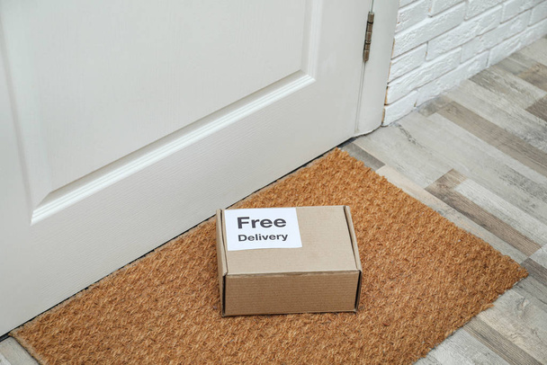 Parcel with sticker Free Delivery on rug indoors. Courier service - Zdjęcie, obraz