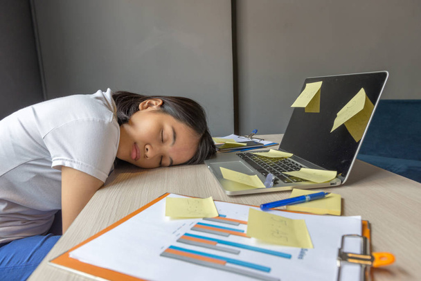 Exhausted woman sleeping on the unorganized desk - 写真・画像