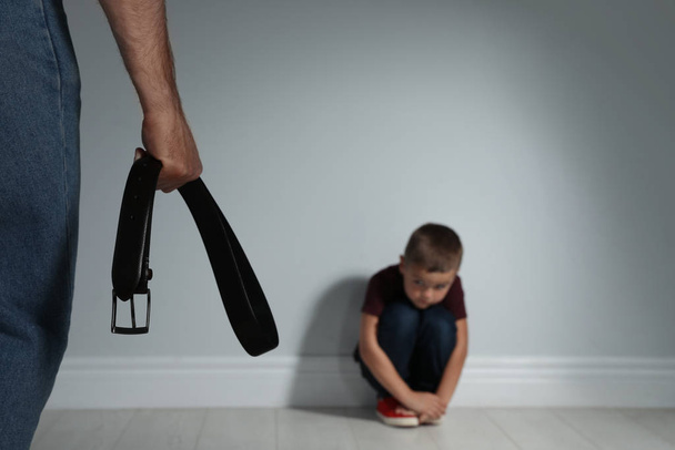Man threatening his son with belt indoors. Domestic violence con - Фото, изображение