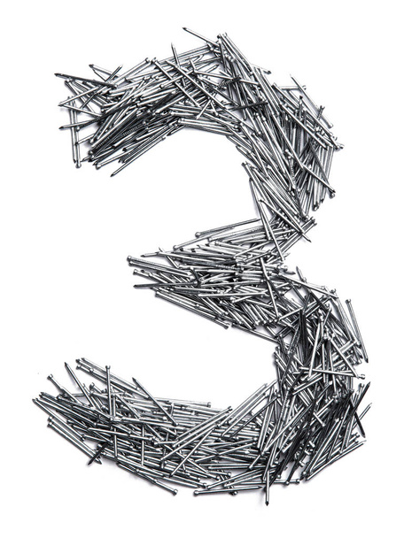 Numero arabo "3" da piccoli chiodi di ferro su uno sfondo bianco isolato. Modello industriale di unghie sottili per elementi di fissaggio. numero luminoso per il design
.  - Foto, immagini