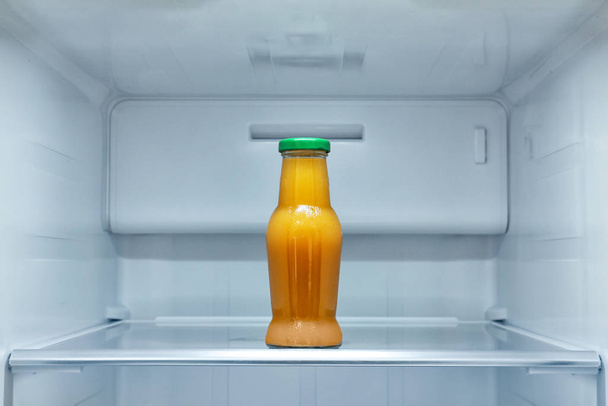Bottle of juice on shelf in refrigerator - Φωτογραφία, εικόνα