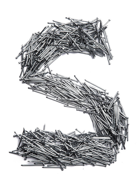 Letter S of the English alphabet from small iron nails  on a white isolated background. Industrial pattern of thin nails for fasteners. bright  numeral for design.  - Photo, Image