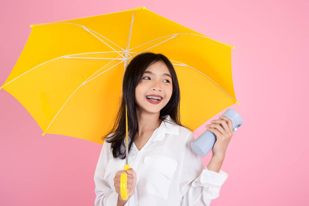 Asian teenager girl holding yellow umbrella during cold rainy da - Foto, immagini