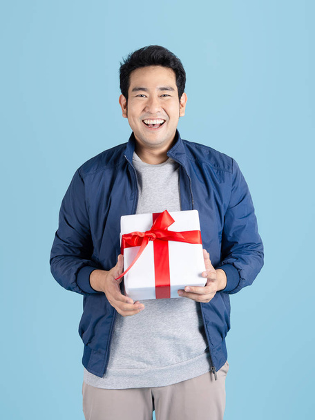 Delivery man is carrying gift box to customer isolated on blue b - Foto, Bild