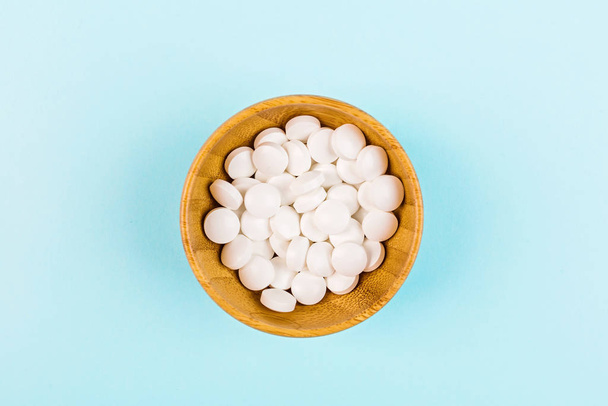 White pills on a pastel blue background. Flat lay, top view, overhead, mockup, template, copy space. Pharmacy and medical concept - Foto, immagini