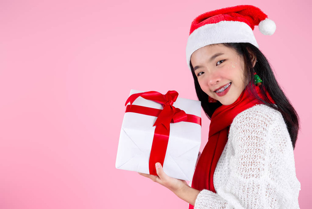 Happy Asian teenager girl holding gift boxes on pink  background - 写真・画像