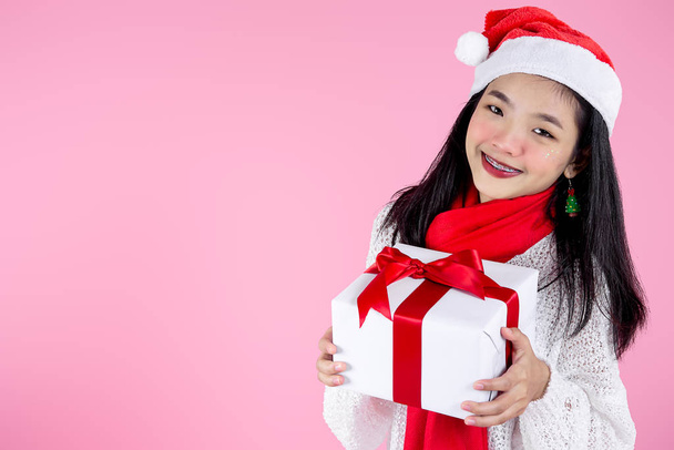 Happy Asian teenager girl holding gift boxes on pink  background - Zdjęcie, obraz