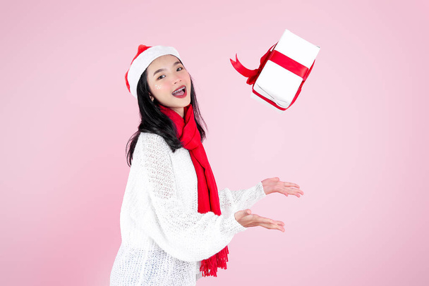 Happy Asian teenager girl throwing gift box on pink background,  - 写真・画像