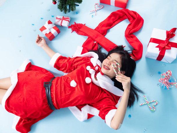 Asian teenager girl wearing Santa Claus costume lying on floor w - 写真・画像