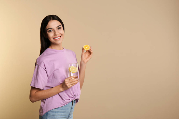 Beautiful young woman with tasty lemon water and fresh fruit on  - Foto, Imagen