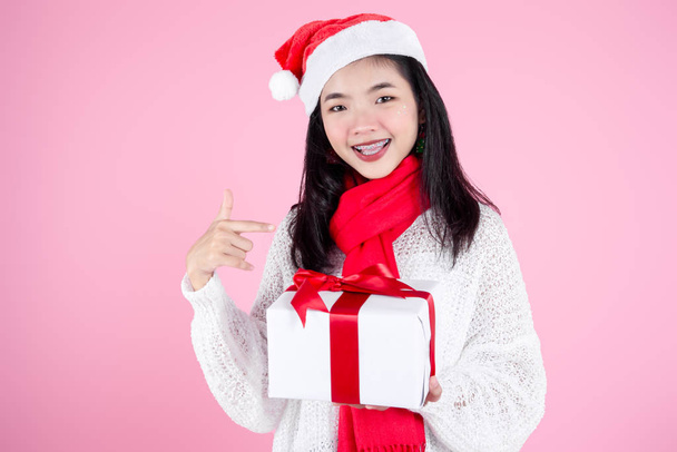 Happy Asian teenager girl holding gift boxes on pink  background - Photo, Image