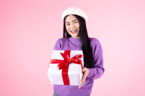 Happy Asian woman wearhing purple sweater holding gift box on pi - Fotó, kép