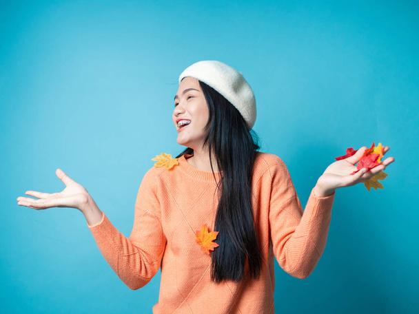 Happy Asian woman wearing sweater and playing with dropping mapl - Foto, afbeelding