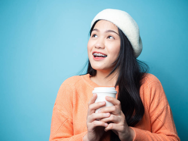 Happy Asian woman wearing sweater and drinking coffee take away  - Фото, изображение
