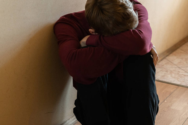 депресивний нещасний чоловік сидить на підлозі в коридорі
 - Фото, зображення
