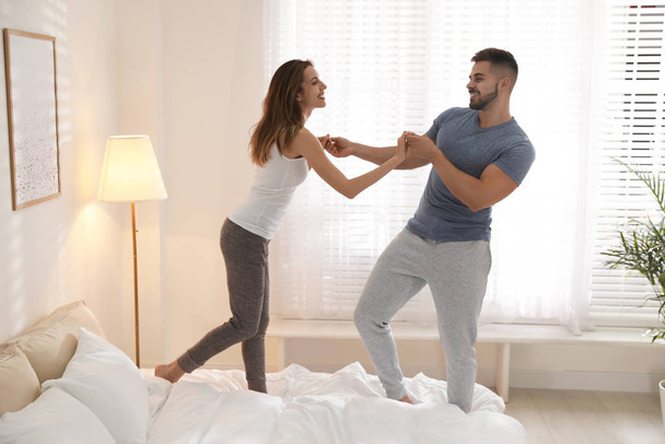 Lovely young couple dancing on bed at home - Foto, Bild