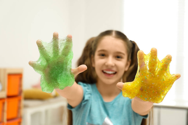Preteen girl with slime in playroom, focus on hands - Фото, зображення