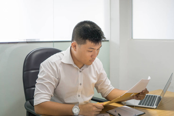 Empresario asiático leyendo documento financiero en la oficina
 - Foto, Imagen