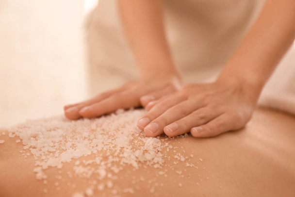 Young woman having body scrubbing procedure with sea salt in spa - Zdjęcie, obraz