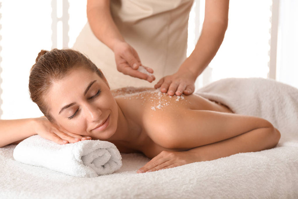 Young woman having body scrubbing procedure with sea salt in spa - Photo, Image