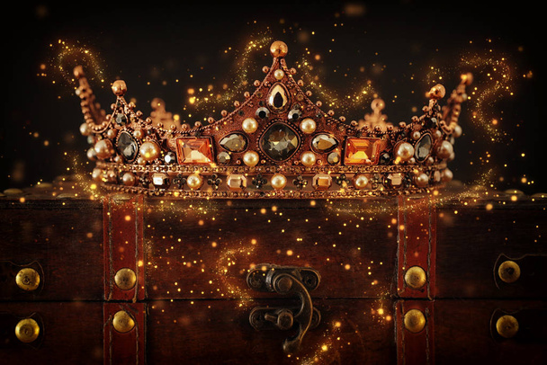 low key image of beautiful queen/king crown over wooden table. vintage filtered. fantasy medieval period. Glitter sparkle lights - Foto, imagen