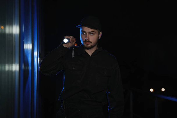 Male security guard with flashlight in dark corridor - Фото, зображення