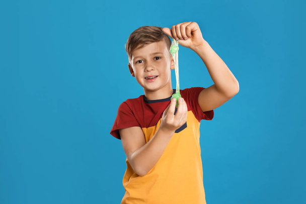 Preteen boy with slime on blue background - Foto, afbeelding