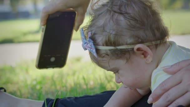 Mobiele telefoon die wordt gebruikt om een foto te maken van een baby in het park - Video